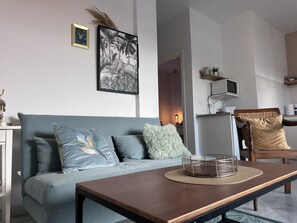 A living room with a sofa, a coffee table, and a chair. There is a framed picture on the wall and a small plant on the table. - Apartamento El Convento - Ole Solutions (Jerez de la Frontera)