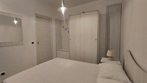 Une chambre à coucher avec un lit, une table de chevet avec une lampe, une armoire et un miroir au mur.