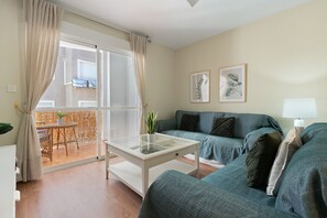 Un salon comprenant une table basse avec un plateau en verre, un canapé et un coin repas avec une table et des chaises.