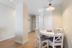 Un coin repas avec une table ronde, des chaises blanches et un luminaire suspendu.
