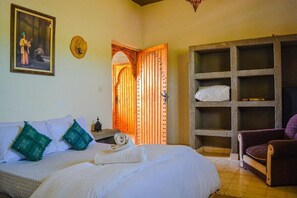 A bedroom with a bed, a wooden wardrobe, a purple armchair, and a painting on the wall. - Villa Mama Vus panoramique sans vis-à-vis (Essaouira)