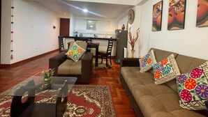 Una sala de estar con sofá, sillas, una mesa de centro y un comedor con mesa y sillas.