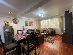 A living room with a dining area, a sofa set, a refrigerator, and a ceiling fan. - San Blas Cusco Apartment (Cusco)