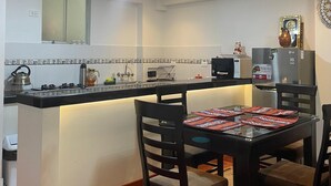 Una cocina moderna con una isla central, una mesa de comedor con sillas y un refrigerador.