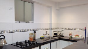 Cocina moderna con encimera negra, armarios blancos, ventana sobre el fregadero y salpicadero con un diseño repetido.