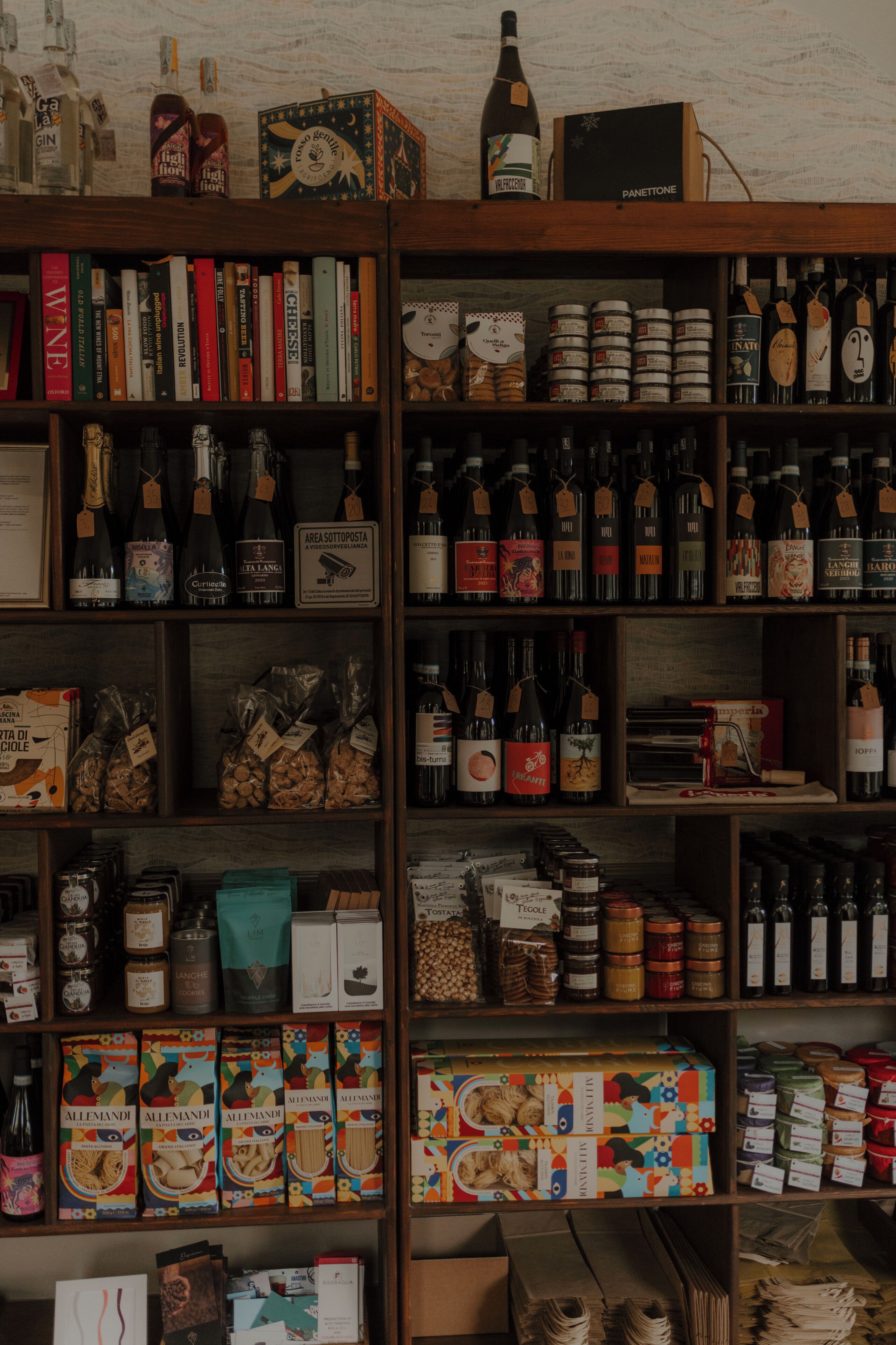 A well-organized shelf with various food items, books, and bottles.