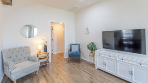 Una sala de estar con un sofá, una silla, un televisor y un mueble.