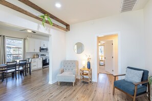 A spacious living area with a dining table, two chairs, a tufted armchair, a side table with a lamp, a round mirror, and a blue sofa. - Spacious 4-bedroom house centrally located in beautiful Belton, Tx (Belton)