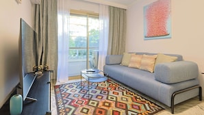 A living room with a sofa, a flat-screen TV, a patterned rug, and a window with curtains. - 324 Le Fleuri in Cannes (Cannes)