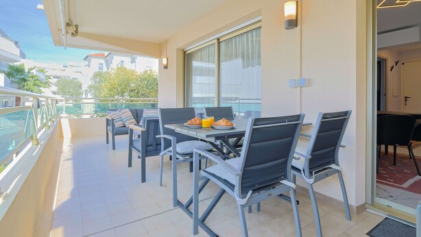 Ein Balkon mit Esstisch, Stühlen und Glasgeländer.