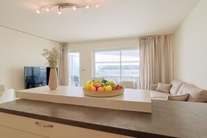 Un soggiorno moderno con una TV a schermo piatto, una ciotola di frutta, un vaso e un divano.