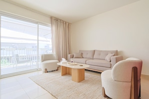 A modern living room with a sofa, armchairs, a coffee table, and a large sliding glass door leading to an outdoor balcony. - 220 Le Maria in Cannes (Cannes)