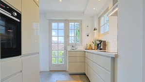 A modern kitchen with white cabinetry, a built-in oven, a window, and a small island with a coffee maker. - 221 Le Bella in Cannes (Cannes)