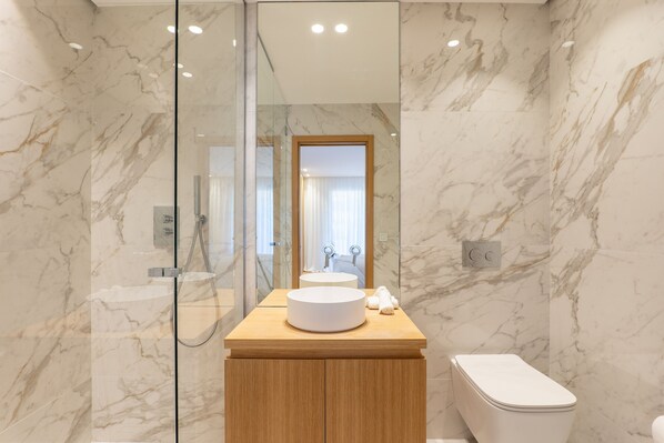 A modern bathroom with a marble wall, a wooden vanity, a round sink, and a toilet. - 002 Villa Camille in Cannes (Cannes)