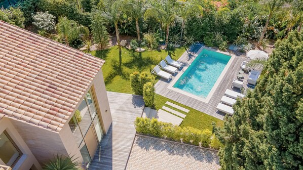 A rooftop pool with lounge chairs, surrounded by greenery and a tiled roof. - 002 Villa Camille in Cannes (Cannes)