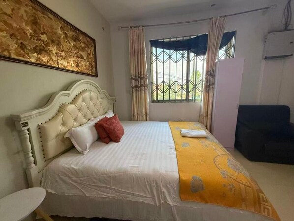 A room with a bed, a round table, a window with curtains, and a painting on the wall. - Huayun Primier Hotel (Accra)