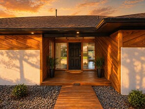 A modern house with a wooden exterior, a front door, and a small porch area. - Luxury 4BR Family Retreat w/Pool Sleeps 10 6 Beds (Dallas)