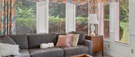 A living room with a sectional sofa, ottoman, and a wooden tray on the floor.