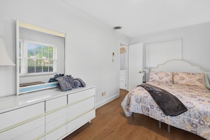 A bedroom with a bed, a dresser, a mirror, and a window with blinds. - Muirs Chapel Retreat spacious 4BR Near Airport & Hospitals - business & vacation (Greensboro)