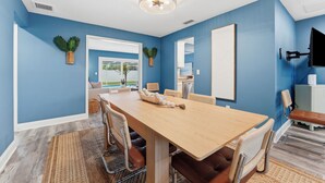Zona pranzo con tavolo in legno, sedie e ventilatore a soffitto.