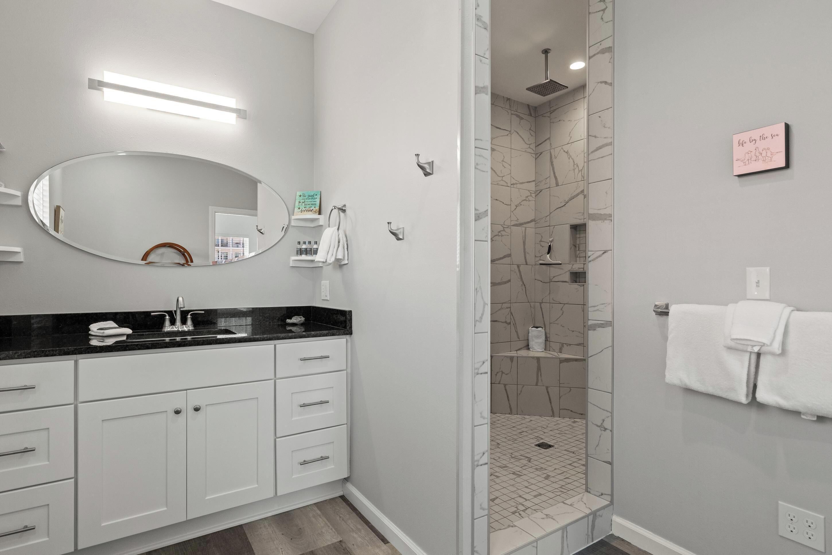 Une salle de bain moderne équipée d’un meuble-lavabo, d’un miroir, d’une douche et d’un porte-serviettes.