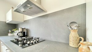 Eine Küche mit Gasherd, Kaffeemaschine, Wasserkocher und einer Keramiktasse.