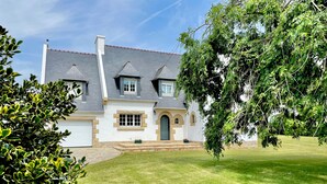 Ein zweistöckiges Haus mit Naturstein-Fassade, einer Garage und einem gepflegten Rasen.