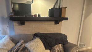 A living room with a grey sofa, a black fireplace, and a wooden floor. - Tranquil 3-bedroom apartment with AC in Pittsburgh Oakland area. (Pittsburgh)
