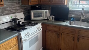 A kitchen with wooden cabinets, a microwave, a stove, and a sink. - Tranquil 3-bedroom apartment with AC in Pittsburgh Oakland area. (Pittsburgh)