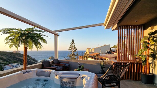 Terraço no telhado com banheira de hidromassagem, cadeiras de descanso e vista para o oceano.