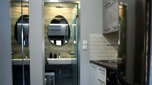 Uma cozinha moderna com geladeira de aço inoxidável, armários brancos e um painel de vidro.