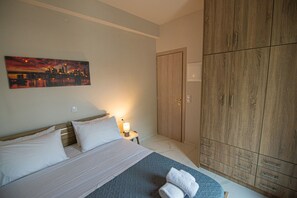 Ein Hotelzimmer mit Bett, einem Gemälde, einem Schrank und einem Nachttisch mit Lampe.
