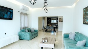 Una sala de estar moderna con sofás color turquesa, una mesa de centro de madera y un comedor al fondo.