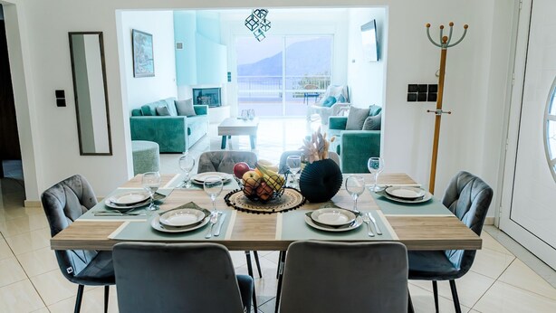 Un comedor con una mesa dispuesta para seis, un frutero y vistas a un balcón con mobiliario exterior.