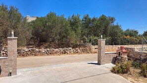 Ein gepflasterter Weg führt zu einer Steinmauer mit einem kleinen Gebäude, das einer Kirche oder Kapelle ähnelt.