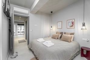 Ein Schlafzimmer mit einem Bett, Kissen, einem roten Nachttisch und Bildern an der Wand.