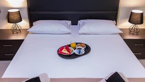 Una camera d'albergo con un letto, due comodini, un quadro e asciugamani sul letto.