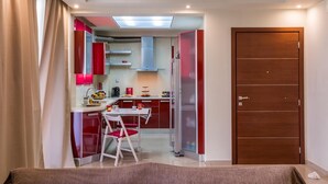 Una cucina compatta con zona pranzo, una porta in legno e una plafoniera.