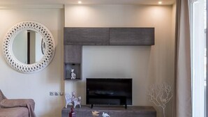 Un soggiorno moderno con televisione a schermo piatto, un tavolino da caffè con oggetti decorativi, un divano e un grande specchio.
