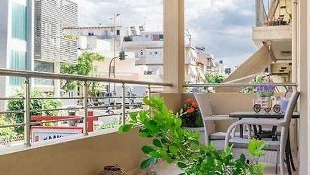 Un balcone con vista su edifici, una pianta in vaso e un tavolo con sedie.