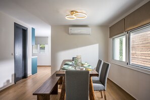 Un comedor con una mesa de madera, sillas y un equipo de aire acondicionado.