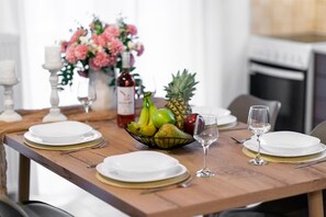 A dining table set with plates, cutlery, a fruit bowl, a wine bottle, and a vase with flowers. - Elva Luxury Villa with private pool (Elea)