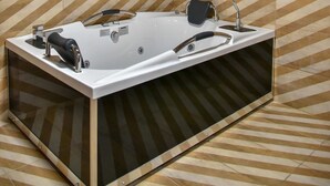 A modern bathroom with a freestanding bathtub, wooden ceiling beams, and patterned tile walls. - Villa 4 season: Poolside Paradise in Crete (Agia Varvara)