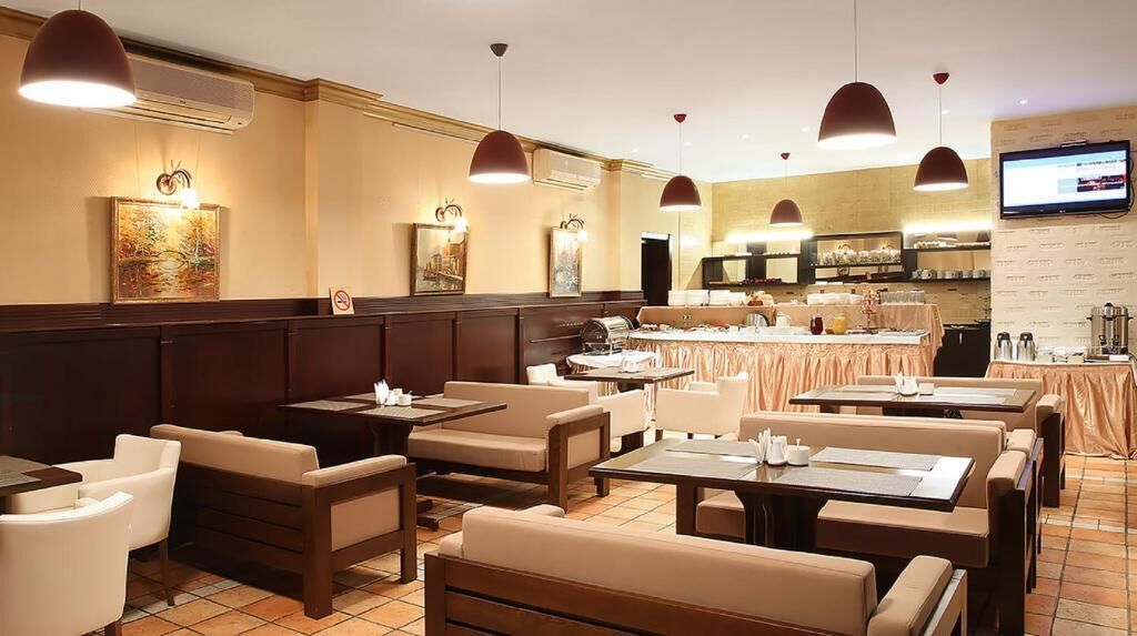A restaurant with booths and tables, a kitchen in the background, and a TV mounted on the wall.