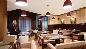 A hotel dining area with multiple tables and chairs, pendant lighting, and a large window with blinds. - Kalasi Hotel (Tbilisi)