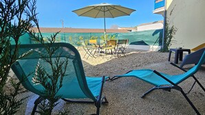 Eine Terrasse mit einem grünen Stuhl, einem blauen Liegestuhl und einem Tisch mit Sitzgelegenheiten.
