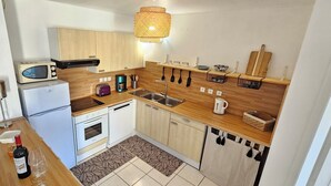 Eine kleine Küche mit Holzschränken, einem Backofen, einer Mikrowelle, einem Spülbecken und einer Kaffeemaschine.