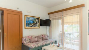 Una sala de estar con un sofá, un televisor de pantalla plana, un cuadro y un ventanal corredera.