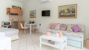Una stanza moderna e luminosa, dotata di angolo cottura, zona pranzo, divano e TV a parete.