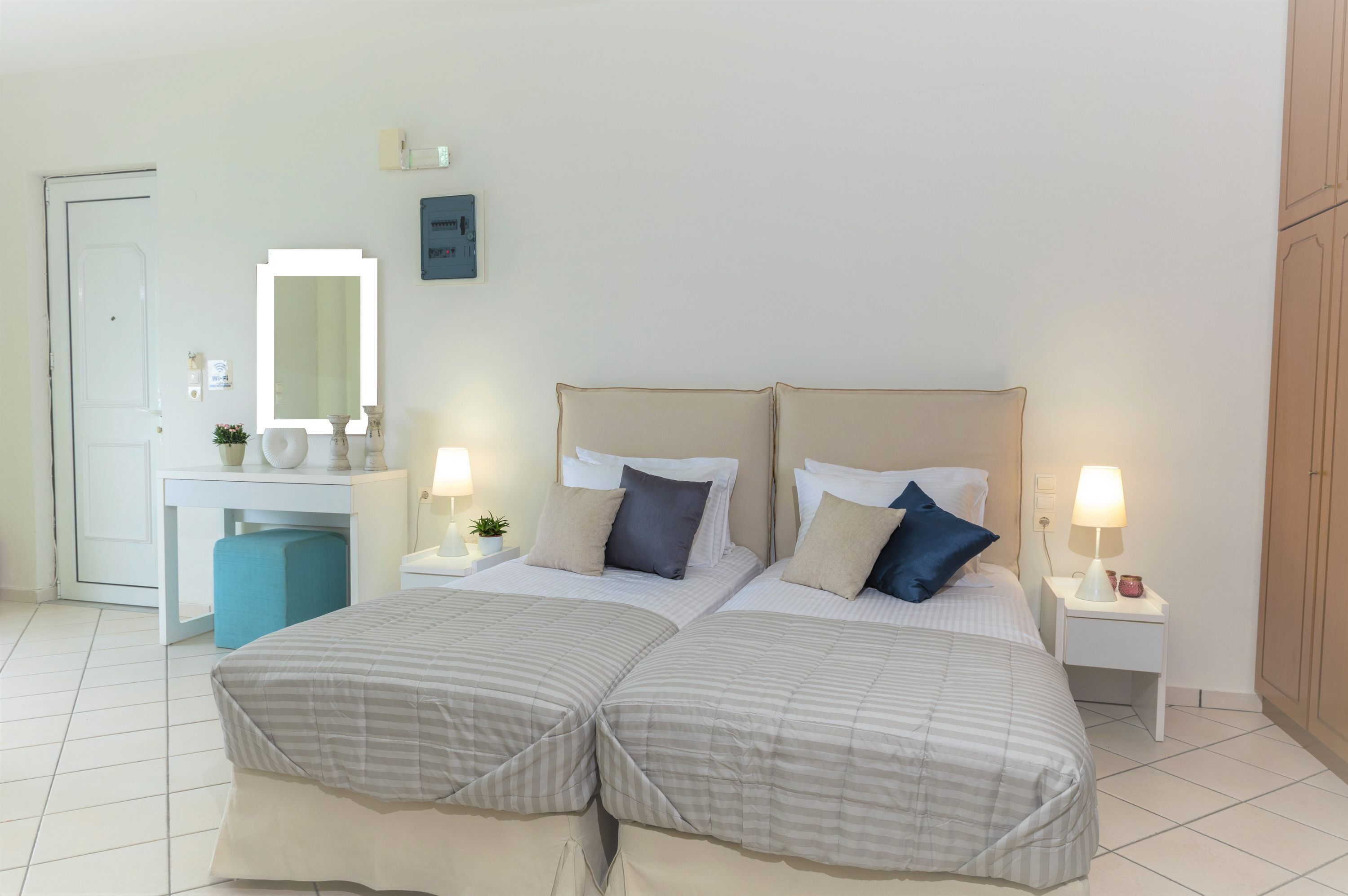 Un lit double avec deux tables de chevet, une commode, un bureau avec une chaise, un miroir et une armoire.